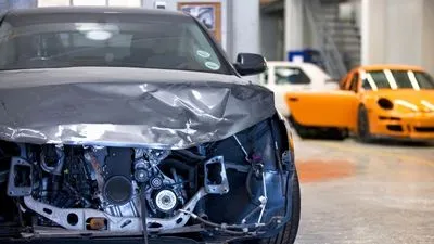 Man repairing damaged car at auto body shop